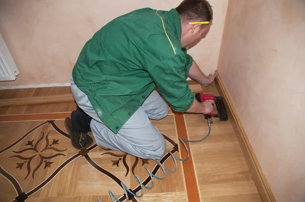 修理工安装踢脚板板栎木地板用胶水 地板和修复 承建商锤击橡木木制护墙板实木复合地板 — 图库照片
