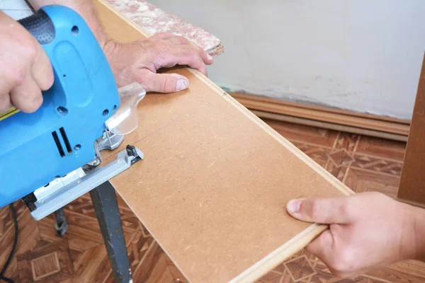 承建商切割复合地板纵向。用电锯切割工人强化木地板. — 图库照片