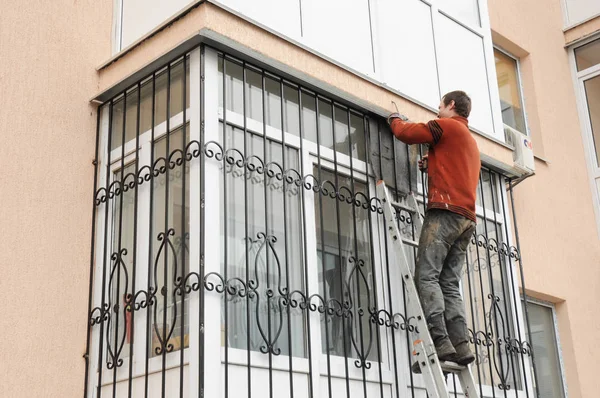 KIEV, UCRANIA - SEPTIEMBRE, 15, 2017: Trabajador instalar barras de seguridad de hierro ventana para la seguridad de la casa. Contratista instalar barras de seguridad de hierro ventana con soldadura. Persianas de seguridad Rejillas Instalación . — Foto de Stock