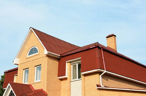 Mansard roof and roof gutter. Modern Brick House Facade Exterior. Modern House Construction. Hip and Valley roofing types.