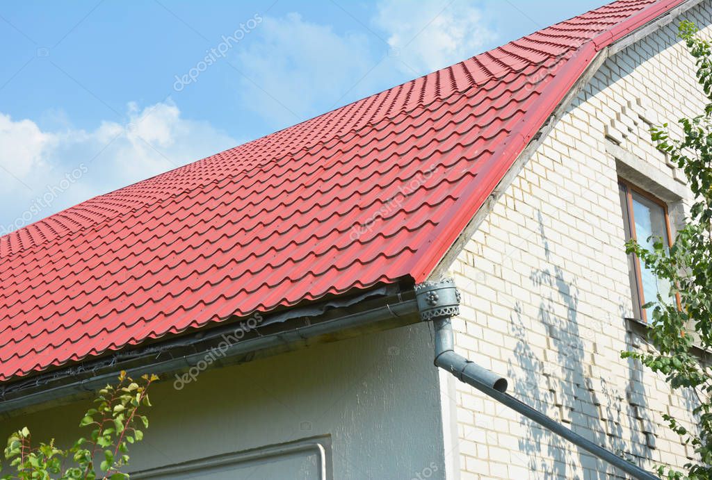 Building new house with metal red roof repair, roofing construction outdoor with old metal rain gutter and metal rain chain.