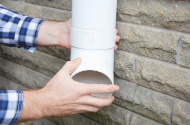 İşçi yükleme yağmur oluk downspout boru. Yüklenici eller onarım yağmur oluk downspout boru. Yaşamadönüşmesi, yağmur zincir drenaj.