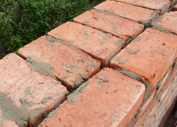 Puesta de ladrillo en el sitio de construcción de casas. Construyendo muro de ladrillos. Ladrillo albañilería juntas pared exterior . — Foto de Stock