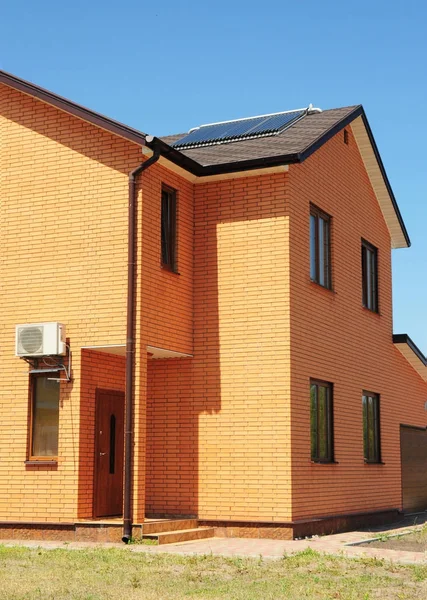 Toit en bardeaux d'asphalte avec système de gouttière de pluie et panneau solaire, système de chauffage solaire de l'eau sous vide. Maison en brique avec construction de toiture à efficacité énergétique . — Photo