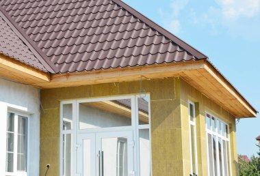 Metal çatı ve taş duvar izolasyonu bitmemiş soffits ve fasya kurulları ile yükleyin. Ev duvar izolasyonu.
