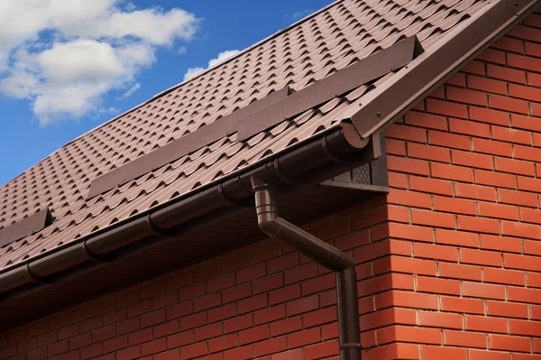 Close-up op regen goot systeem met regenpijp pijpleiding en metalen dakbedekking. Bakstenen huis dak bescherming tegen sneeuw Board (sneeuw Guard). — Stockfoto