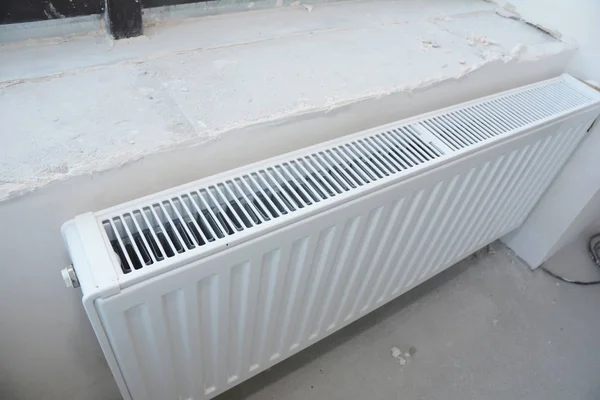 Installazione di riscaldamento radiatore in metallo bianco con termostato nella nuova costruzione della casa . — Foto Stock