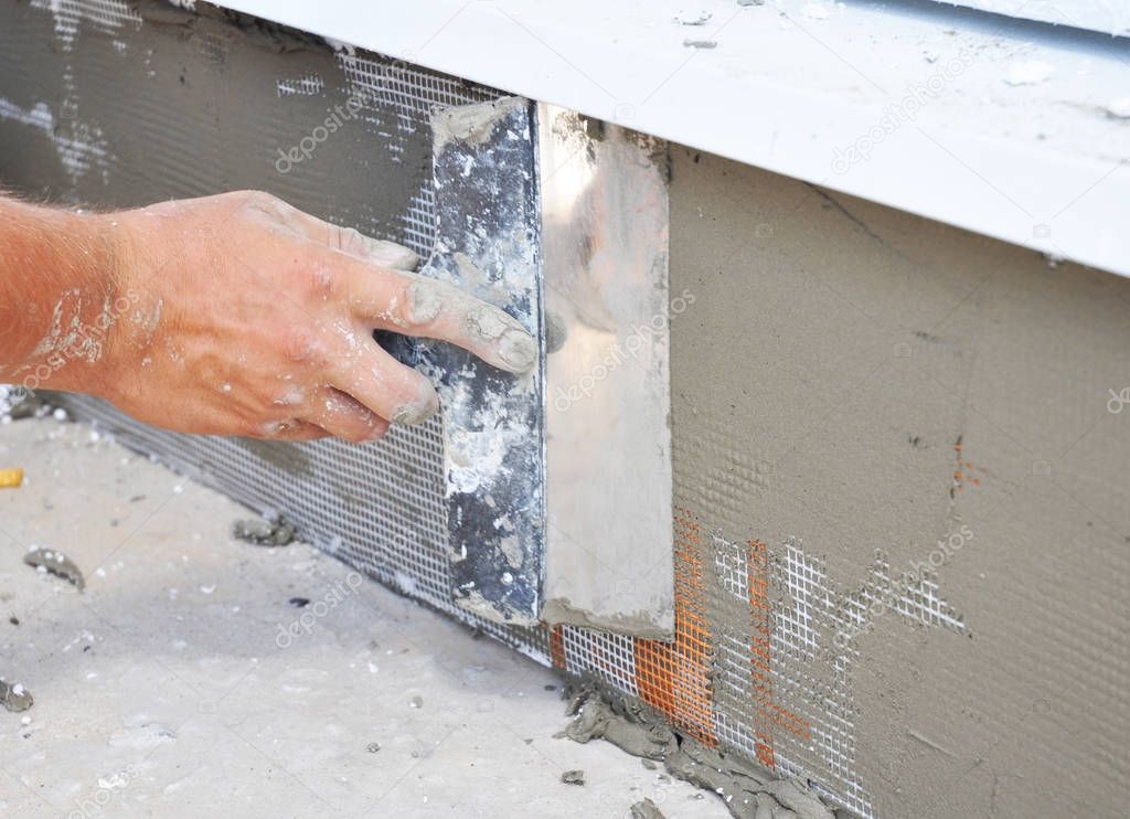 Contractor plastering foundation wall after rigid styrofoam insulation 