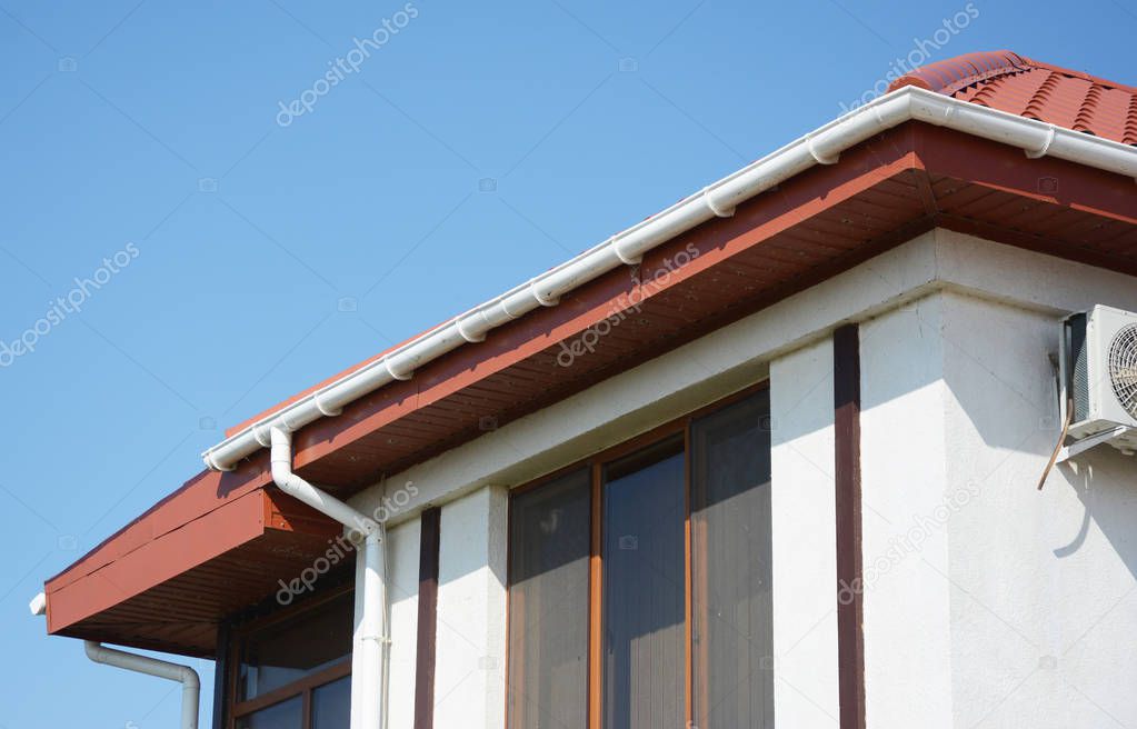 Red metal attic house roof with plastic roof guttering system.