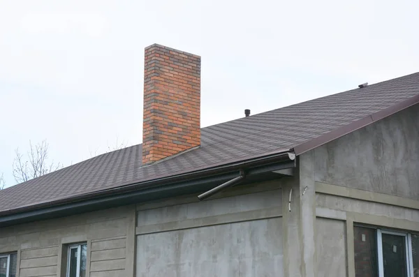 Construção de nova casa com telhas de asfalto coberturas, ventilação, sistema de calha de telhado e chaminé de tijolo . — Fotografia de Stock
