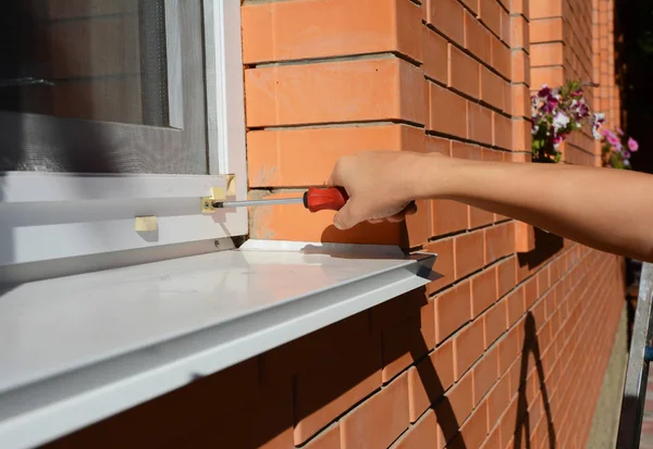 Worker installing mosquito net,  mosquito wire screen on brick house window.