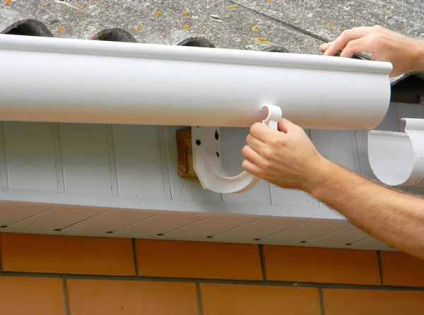 Contratista instalando cuneta de techo de plástico. Canaletas de plástico, canaletas de lluvia y drenaje por manos de Handyman . —  Fotos de Stock