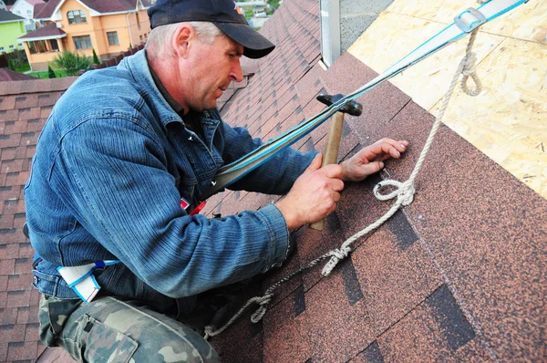 KYIV, UKRAINE - October, 24, 2017:  Roofer laying asphalt shingles. Roofer with safety kit on the house roof installing, repair asphalt shingles. — Stock Photo, Image