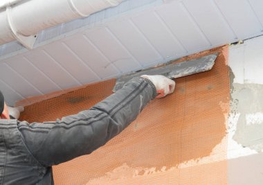 Yüklenici sıva duvar ile macun spatulası, fiberglas ağ, alçı kafes sonra katı yalıtım. 