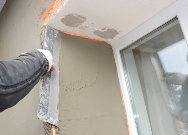 Builder plastering wall with spatula, fiberglass mesh, plaster mesh after foam rigid insulation. Window sill area insulation with stucco wall. — Stock Photo, Image