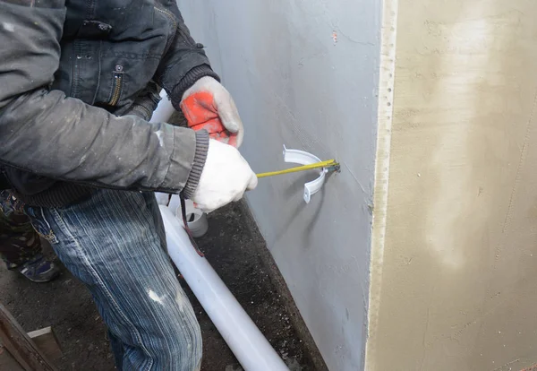 Auftragnehmer installieren Regenrinnen-Ablaufrohrhalter mit Maßband. Dachrinnen — Stockfoto