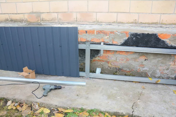 Reparación de la pared de cimentación de la antigua casa, renovación con la instalación de láminas de metal para impermeabilizar y proteger de la lluvia . — Foto de Stock