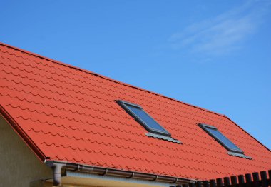 Işıklık Attic Windows kırmızı Metal ev çatı ile kapatın. Modern ev tavan arası çatı su yalıtım.