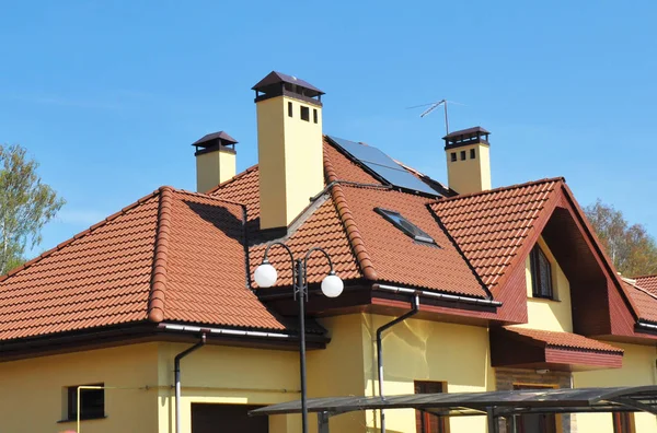 Modern house attic roof with skylight windows, roof gutter, chimneys and solar panels — Stock Photo, Image