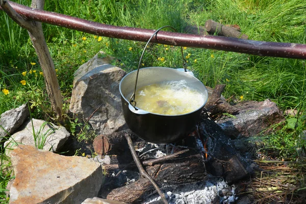 Camp cooking soup in the cauldron on the open fire.