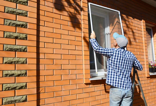 Arbetstagare installera myggnät eller mygga tråd skärmen på tegel hus fönster. — Stockfoto