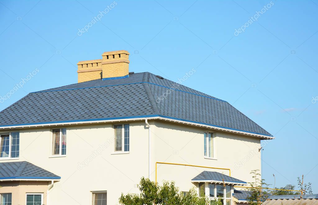House roof with Asphalt shingles, ventilation, chimney and roof gutter pipeline outdoors. 