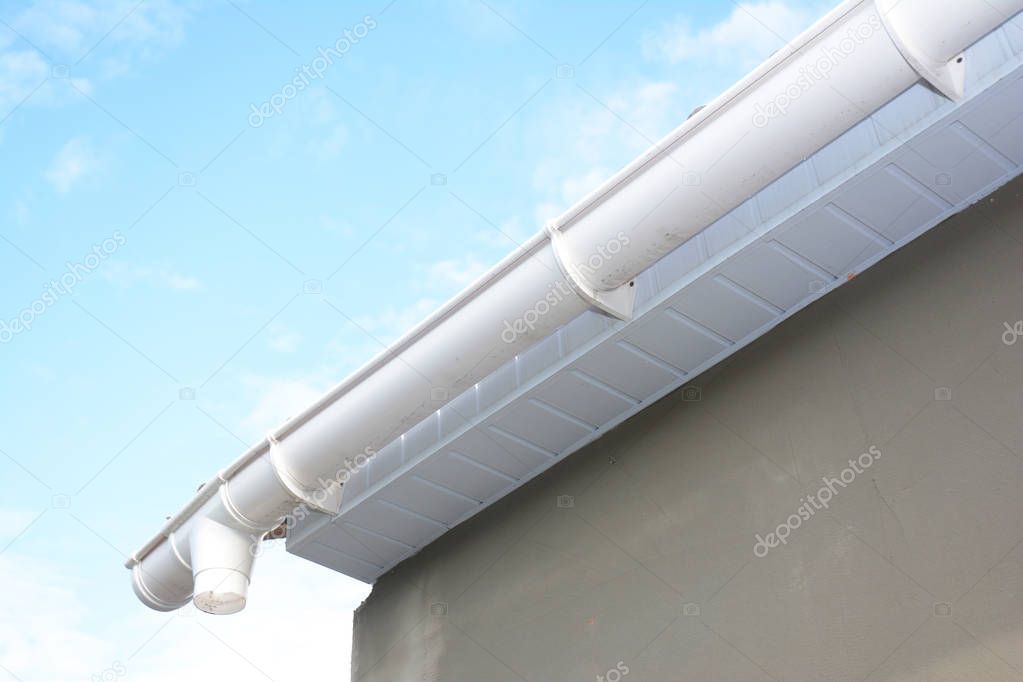 Roof gutter repair. Rain gutter installation with drain downspout pipe. 