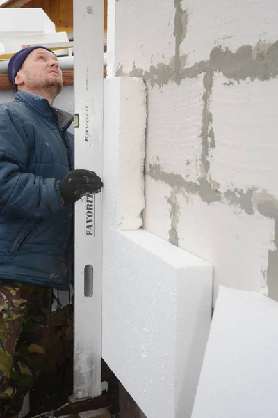 Будівельний підрядник ізоляційні стіни будинку з пінополістиролу ізоляції аркушів. Працівник вимірювання пінополістиролу ради з духом рівня. — стокове фото