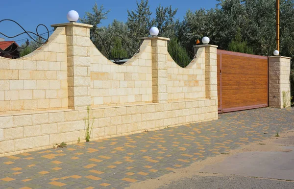 Stone fence with gate and entrance door. House fencing.