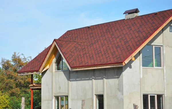 Bouw huis met nieuwe asfalt shingles dakbedekking en gips muur buiten. Dakbedekking constructie met rood asfalt gordelroos. — Stockfoto