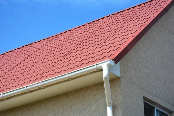 Red metal roof with white plastic rain gutter. — Stock Photo, Image