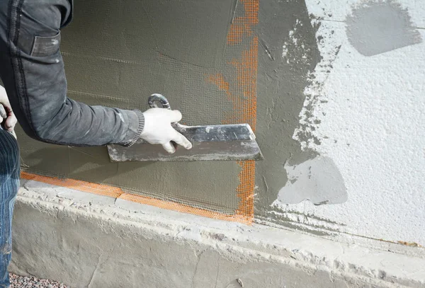 Contratista pared de enlucido con espátula, malla de fibra de vidrio, malla de yeso después de aislamiento rígido . — Foto de Stock