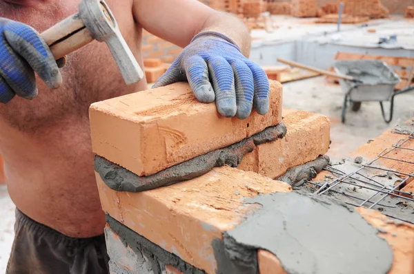 How to lay bricks: Bricklayer laying bricks with hammer.  Masonry Construction.