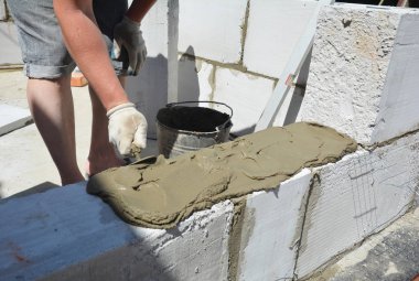 Otoklavlı beton bloklar döşeyen tuğla ustası, Aac. Otoklavize edilmiş beton bloklar beton yapıştırıcılı duvar kurulumu