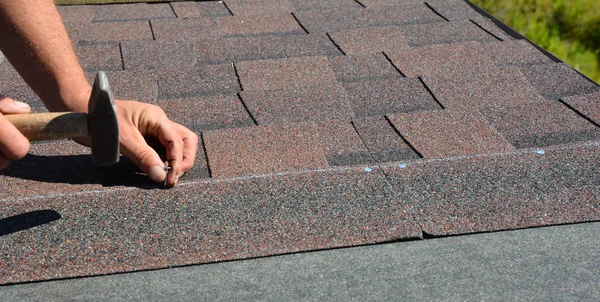 Dłonie dachowe instalowanie gontów asfaltowych na dachu domu budowy rogu z młotem i gwoździami. Panorama konstrukcji dachu zdjęcie. — Zdjęcie stockowe