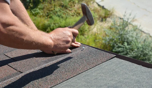 Roofer with hammer in motion, laying asphalt shingles tiles on house roof. Roofing Construction panorama photo — Stock Photo, Image