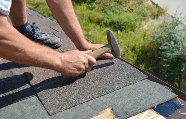 Construção de telhados. Telhado com martelo e unhas que colocam telhas asfalto no telhado da casa . — Fotografia de Stock