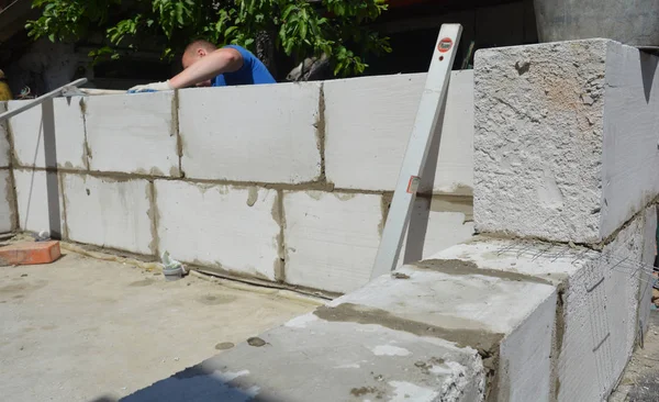 Baksteen bouwer leggen autoclaaf beluchte betonnen blokken voor huis muur. — Stockfoto