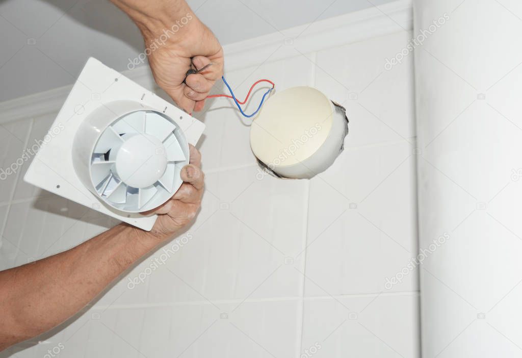 Handyman installing new bath vent fan, ventilation system in the house bathroom . Bath fan repair, installation.