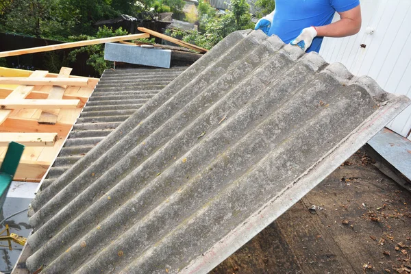 Asbest temizleyicisi çatı tamircisi çalışıyor. Eski, tehlikeli asbest çatı kiremitleri onarılan ve yenilenen bir ev. Asbest Çatı Riskleri, Asbest Çatı Temizleme. — Stok fotoğraf