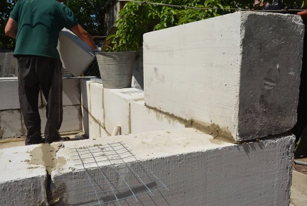 Bricklayer builder laying autoclaved aerated concrete blocks, aac for new house wall. Autoclaved aerated concrete blocks walling installation — Stock Image Bricklayer builder laying autoclaved aerated concrete blocks, aac for new house wall. Autoclaved aerated concrete blocks walling installation Stock Image