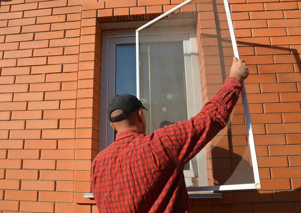 Reparador instalando mosquitero en ventana de la casa — Foto de Stock