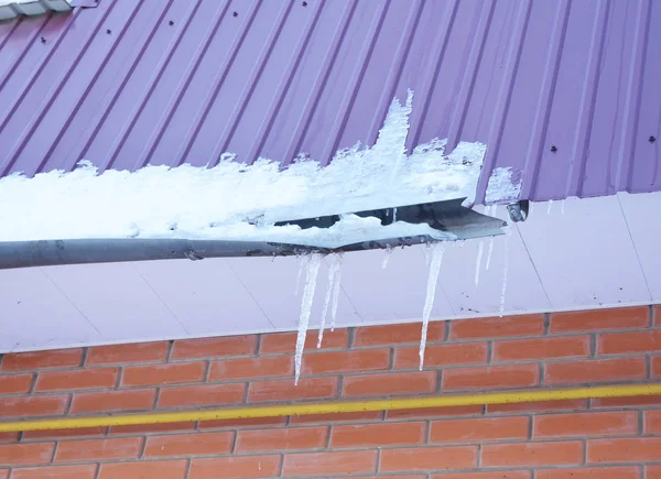 Grondaia danneggiata da ghiaccio e neve. Condotto rotto della grondaia del tetto dai ghiaccioli . — Foto Stock