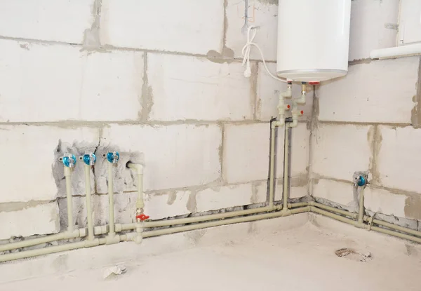 A torneira escondida com tubos conectados é montada na parede e na caldeira elétrica . — Fotografia de Stock
