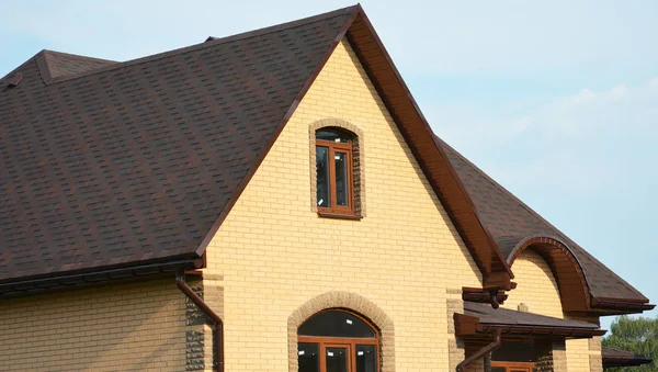 Dachschindeln aus Asphalt. Dachkonstruktion Dachhausbau mit Asphaltschindeln, Regenrinne und Dachlüftung. hautnah auf Asphalt Dachschindeln. — Stockfoto