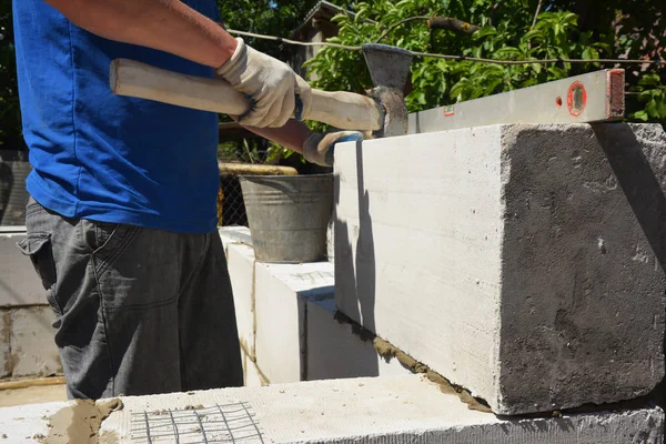 Otoklavlı beton bloklar döşeyen tuğla ustası, yeni ev duvarı için elektrik süpürgesi. Otoklavize edilmiş beton bloklar duvar kurulumu — Stok fotoğraf