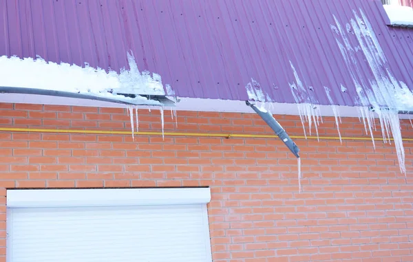 Roof Gutter damaged by ice. Broken plastic rain gutter pipeline by icicles on house rooftop. — 스톡 사진
