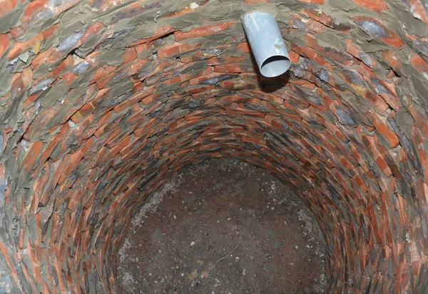 Maison fosse septique de briques rouges. Installation de trou de réservoir en brique d'égout avec tuyau sur le chantier de construction — Photo