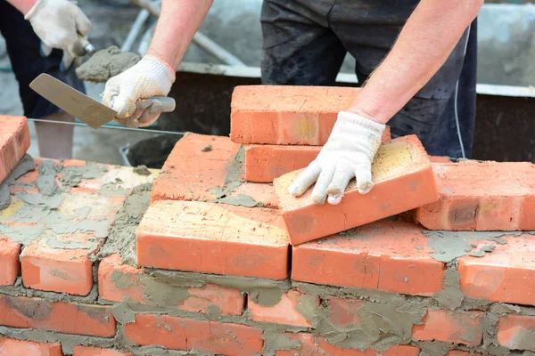 Murare händer i murverk handskar och murslevar murning hus vägg. Byggnadsentreprenörer tegelvägg, murverk. — Stockfoto