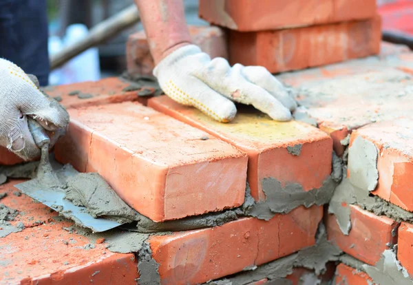 Bricklayer ręce w rękawicach murowanych z kielni kładzenie cegły ściany domu. — Zdjęcie stockowe